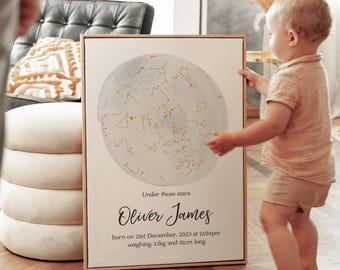 May include: A framed print featuring a celestial map with gold constellations on a light gray background. The text "Under these stars" is above the name "Oliver James". The print includes birth details: born on December 21st, 2023, at 12:04 pm, weighing 6.8 lbs and 20 inches long.