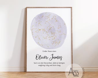 May include: A framed print featuring a watercolor-style celestial map in shades of purple and gold. The text "Under these stars" is above the name "Oliver James". The print includes birth details: December 21, 2023, 12:04 pm, 3.1kg, and 51cm long.