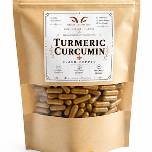 Op de afbeelding: Een bruine papieren zak met een doorzichtig venster, gevuld met kurkuma-curcumine capsules. De zak heeft een label met de tekst "Turmeric Curcumin" en "Black Pepper". Enkele capsules liggen voor de zak.