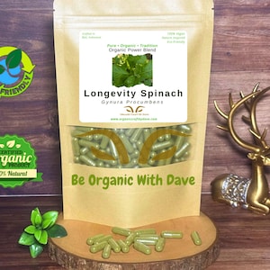 May include: A package of Longevity Spinach capsules, a natural organic power blend. The capsules are green and visible through a clear window. The packaging includes text and logos indicating the product's organic and eco-friendly nature.
