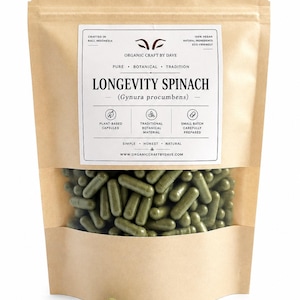 Op de afbeelding: Een bruine papieren zak met een doorzichtig venster met groene capsules. Het etiket luidt "Longevity Spinach (Gynura procumbens)" en "Organic Craft by Dave". De zak vermeldt ook "Plantaardige capsules" en "Kleine partij zorgvuldig bereid".