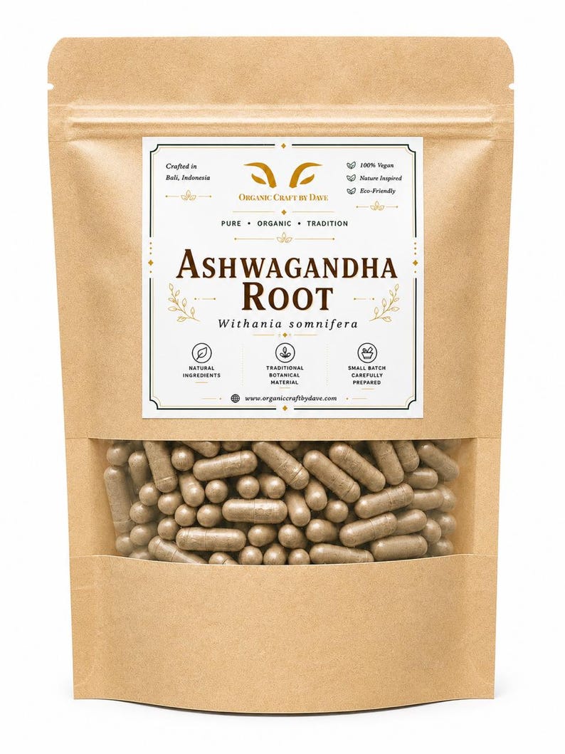 May include: A brown paper bag with a clear window displaying numerous brown capsules. The bag features a label with the text "ASHWAGANDHA ROOT" and "ORGANIC CRAFT BY DAVE". Additional text includes "100% Vegan" and "Natural Ingredients".