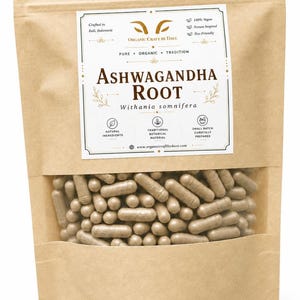May include: A brown paper bag with a clear window, filled with numerous light brown capsules. The bag features a label with the text "ASHWAGANDHA ROOT" and other details about the product, including "Organic Craft by Dave."