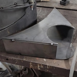 Puede incluir: Un soporte metálico con forma curva y un recorte. El soporte está hecho de metal gris oscuro y tiene un acabado liso.