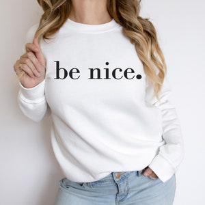 May include: White sweatshirt with the text "be nice." printed in black.