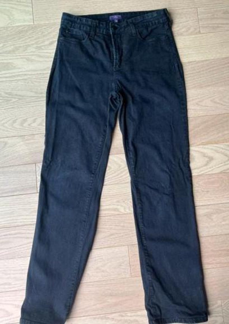 May include: Dark blue denim jeans with a classic five-pocket design. The jeans have a high waist and a straight leg cut. The fabric appears to be a medium-weight denim. The jeans are laid flat on a light wood-grain surface.