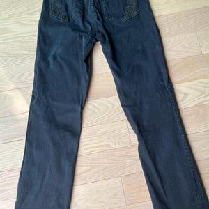 May include: Dark blue denim jeans with embroidered detailing on the back pockets. These jeans feature a classic five-pocket design and a straight leg. The denim appears to be of a medium weight.