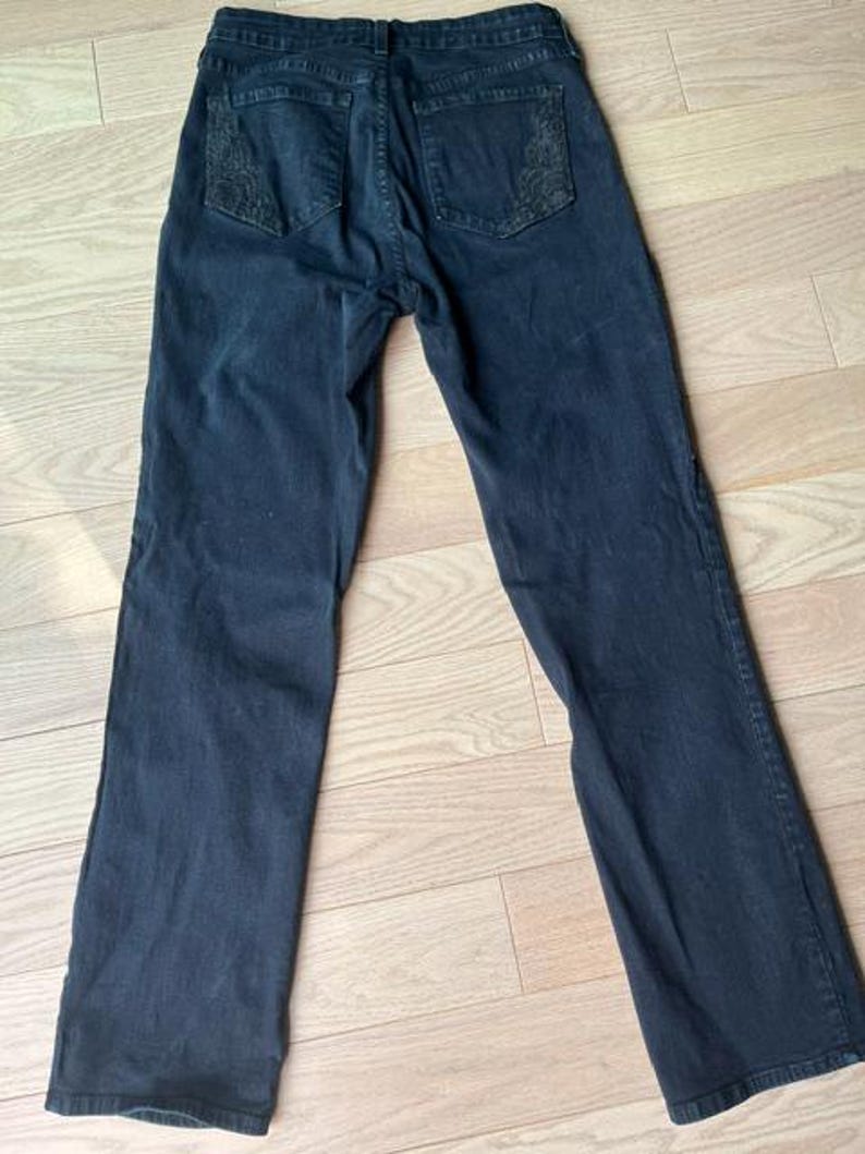 May include: Dark blue denim jeans with embroidered detailing on the back pockets. These jeans feature a classic five-pocket design and a straight leg. The denim appears to be of a medium weight.