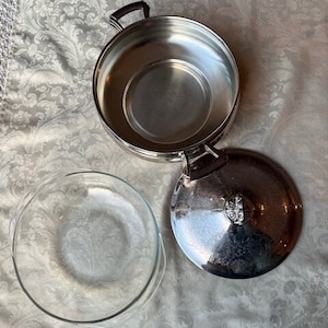 May include: A silver serving dish with a glass insert and a lid. The dish has a decorative design on the lid.