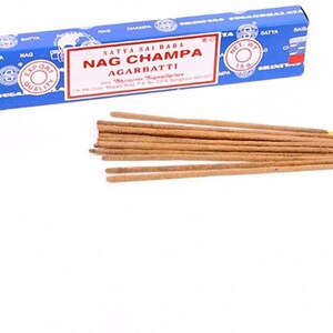 May include: A blue box of Nag Champa incense sticks with the text "Satya Sai Baba Nag Champa Agarbatti" printed on the front. The box is surrounded by a white background. The incense sticks are brown with yellow tips and are arranged in a pile.