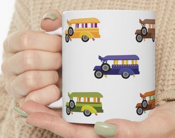Könnte beinhalten: Weiße Keramiktasse mit einem bunten Muster aus Comic-Schulbussen. Die Busse sind gelb, grün, blau und braun mit schwarzen Rädern.
