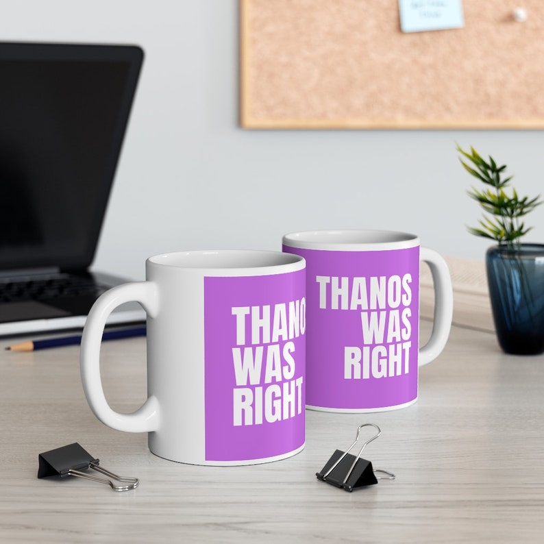 K&ouml;nnte beinhalten: Zwei wei&szlig;e Keramikbecher mit lilafarbenem Hintergrund und wei&szlig;em Text, der "THANOS HATTE RECHT" lautet.