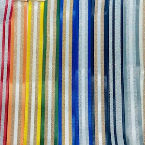May include: Assortment of striped ribbon with gold glitter accents. The ribbons are in various colors including red, orange, yellow, green, blue, and gray.