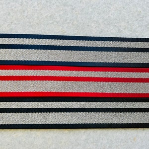May include: Two black and silver striped fabric straps with a red and silver striped fabric strap in the middle.