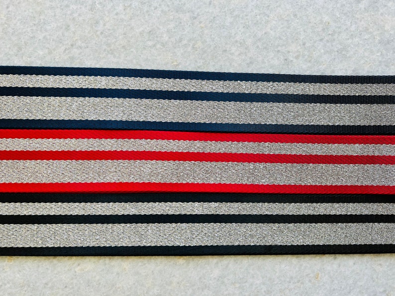 May include: Two black and silver striped fabric straps with a red and silver striped fabric strap in the middle.
