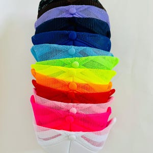 May include: A stack of ten mesh trucker hats in various colours, including black, purple, navy blue, light blue, neon green, neon orange, red, pink, and white.