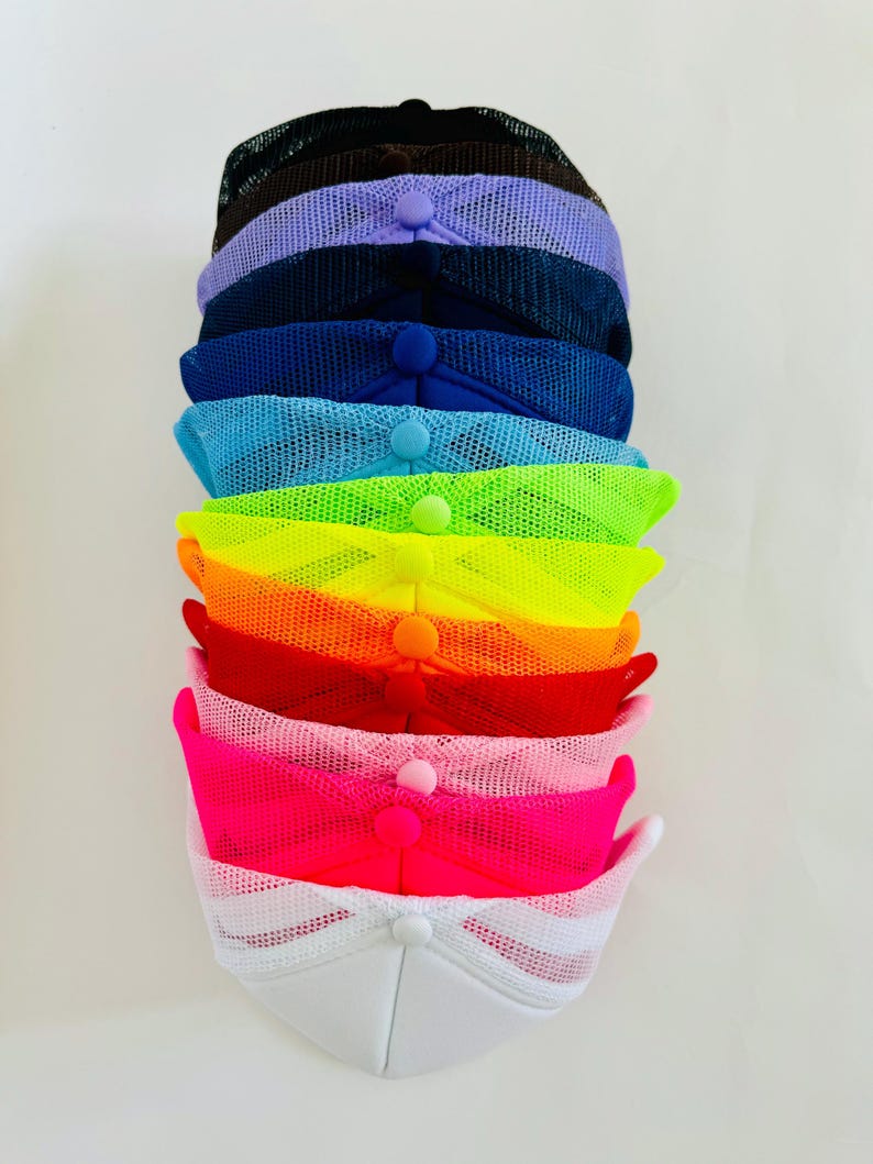 May include: A stack of ten mesh trucker hats in various colours, including black, purple, navy blue, light blue, neon green, neon orange, red, pink, and white.