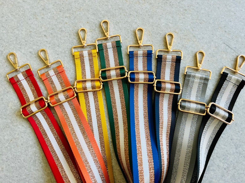 May include: Eight striped fabric straps with gold metal clasps. The straps are in various colors including red, orange, yellow, green, blue, gray, and silver.