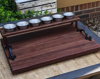 Tabla de charcutería Beer Flight de nogal negro con vasos de degustación, tazas de salsa de acero inoxidable, asas de hierro fundido y patas de goma.