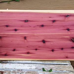 May include: A large rectangular wooden serving tray with two black metal handles. The tray is made of reddish-brown wood with a natural wood grain.