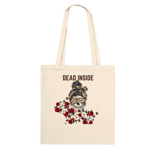 Op de afbeelding: Een beige tote bag met de tekst "DEAD INSIDE" in bruin gedrukt. De tas heeft een afbeelding van een schedel met een luipaardprint knot en zonnebril, omringd door rode rozen.