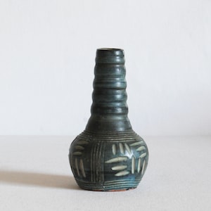 Peut inclure: Un petit vase en céramique bleu foncé avec un col texturé et côtelé et un motif géométrique sur le corps.