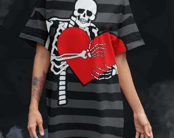 May include: A gray and black striped t-shirt dress featuring a skeleton graphic holding a red heart. The skeleton is white, and the dress has short sleeves. The background is dark with a smoky effect.