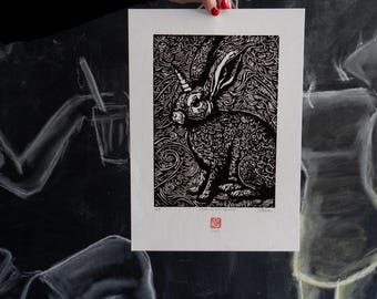 May include: Black and white woodblock print of a rabbit with intricate details. The rabbit is surrounded by a swirling pattern. The print is signed and numbered.