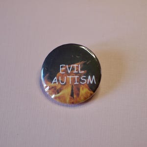 以下が含まれることがあります： 白い文字で「EVIL AUTISM」と書かれた丸いボタン。背景は炎で、印象的なコントラストを生み出しています。