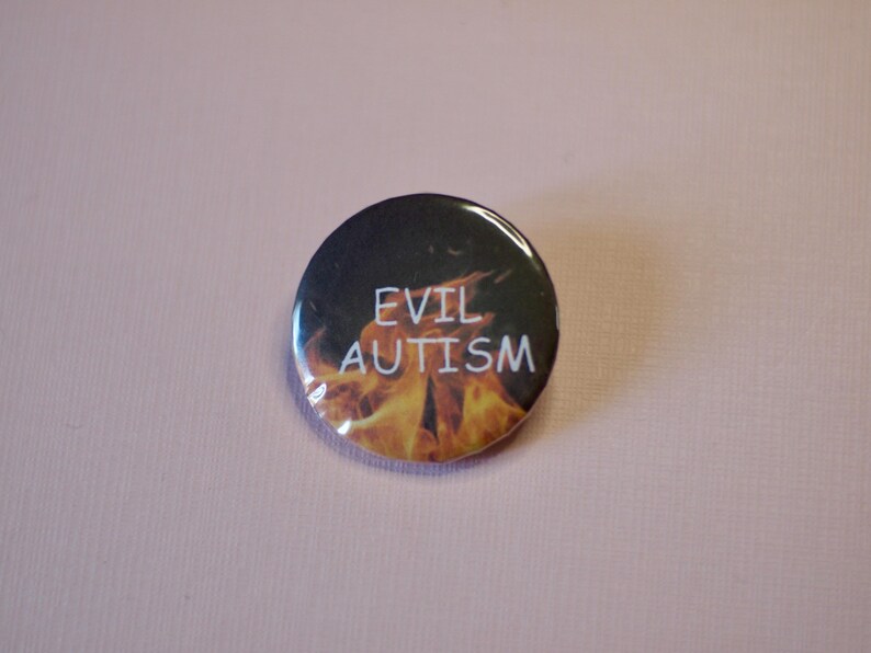 以下が含まれることがあります： 白い文字で「EVIL AUTISM」と書かれた丸いボタン。背景は炎で、印象的なコントラストを生み出しています。