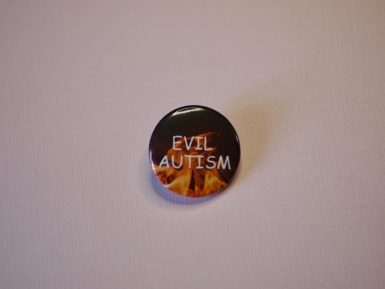 以下が含まれることがあります： 白い文字で「EVIL AUTISM」と書かれた丸いボタン。ボタンの背景には、オレンジと黄色の炎の燃えるようなデザインが施されています。ボタンは黒色で光沢があります。