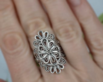 May include: A silver filigree ring with an oval design featuring a floral pattern.