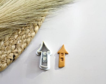Può includere: Un tagliapasta in plastica bianca a forma di casa con tetto a punta e un biscotto di pasta di zucchero marrone tagliato nella stessa forma.