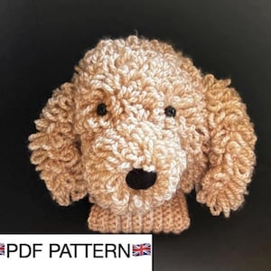 May include: A tan-colored, crocheted dog head with black eyes and a black nose. The dog's fur is textured and curly. The text "PDF PATTERN" is at the bottom of the image.
