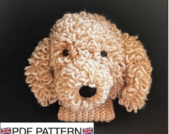 May include: A crocheted dog head in a tan colour, featuring black eyes and a black nose. The dog's fur has a textured, curly appearance. The text "PDF PATTERN" is visible at the bottom.