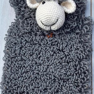 May include: A handmade crochet sheep with a smiling face and a grey body. The sheep has a white head and ears, with a small wooden button. The text "PDF PATTERN" is in the bottom right corner.