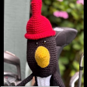 Puede incluir: Una funda de ganchillo para palos de golf con forma de pingüino. El pingüino tiene un cuerpo negro, un gorro rojo, un pico amarillo y ojos negros pequeños. El texto "PDF PATTERN" está en la parte inferior de la imagen.