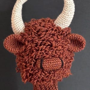 Puede incluir: Cabeza de vaca de las Tierras Altas de ganchillo marrón hecha a mano, con cuernos beige y nariz negra. La imagen incluye el texto "PDF PATTERN". Este artículo es una creación única y hecha a mano.