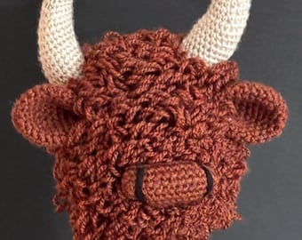 May include: A handcrafted, brown crochet Highland cow head with beige horns and a black nose. The image includes the text "PDF PATTERN". This item is a unique, handmade creation.