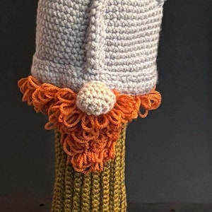 May include: A handmade crochet gnome hat with a gray hat, white horns, and an orange beard. The hat is on a yellow-green base. The image includes the text "PDF PATTERN".