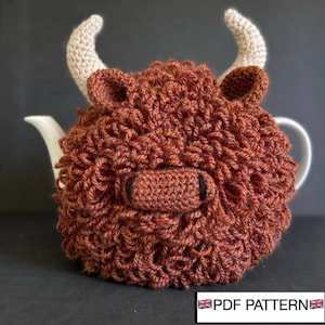 Puede incluir: Un cubreteiera de ganchillo marrón con forma de vaca de las Tierras Altas, con cuernos y orejas color beige. Cubre una tetera blanca, con el pico y el asa visibles. El texto "PDF PATTERN" se muestra en la esquina inferior derecha.