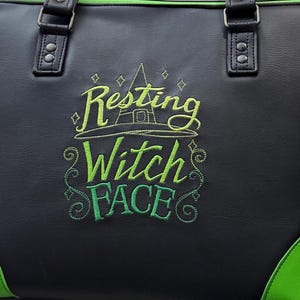 May include: Black tote bag with green accents and handles. The bag features the embroidered phrase "Resting Witch Face" in green and yellow, along with a witch hat design. The bottom corners are green.