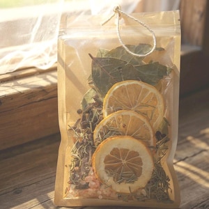 May include: A clear, sealed bag filled with dried herbs, spices, and sliced citrus. The contents include dried lemon slices, bay leaves, and other aromatic ingredients. The bag is tied with a natural twine loop, suggesting a natural product.
