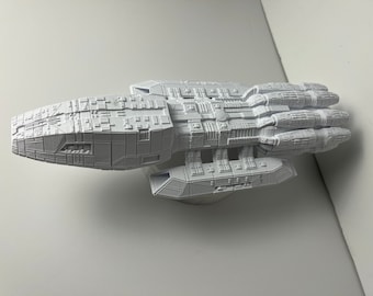 May include: A white 3D printed model of a spaceship with a detailed design and multiple engines.