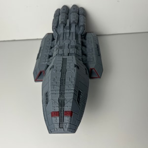 May include: A gray and red spaceship model with a detailed design. The model is made of plastic and has a sleek, futuristic look.