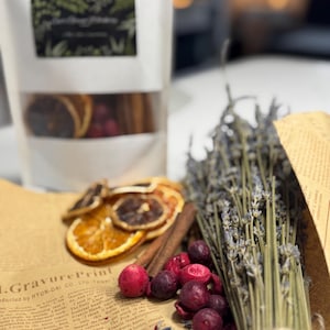 Könnte beinhalten: Nahaufnahme eines braunen Papierbeutels gefüllt mit getrockneten Orangenscheiben, Zimtstangen und Cranberries. Im Vordergrund befindet sich ein Bündel getrockneter Lavendel. Der Beutel trägt ein Etikett mit der Aufschrift "1.GravurePrint" und "HYUN-DAI CO.LTD Tegal T".