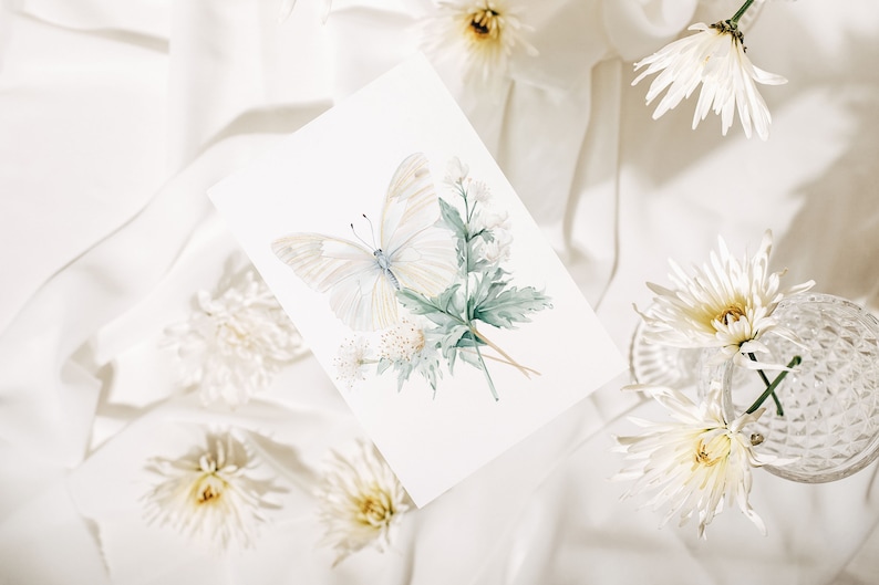 Pu&ograve; includere: Una farfalla bianca con foglie verdi e fiori bianchi su uno sfondo bianco. La farfalla &egrave; dipinta ad acquerello e ha un aspetto delicato ed etereo.