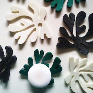 Peut inclure: Un ensemble de sept sous-verres décoratifs en forme de feuilles abstraites en noir, blanc et vert. Les sous-verres sont faits d'un matériau lisse et dur et ont une forme organique unique.