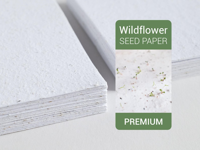 May include: Stacks of white wildflower seed paper with a textured surface. A green label reads "Wildflower Seed Paper" and "Premium". The paper has small flecks and visible seeds.