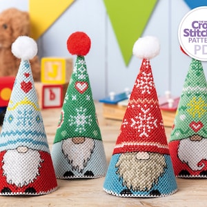 May include: Four gnome-themed Christmas ornaments with different patterns. The ornaments are cone-shaped and feature a red, green, blue, and white color scheme. Each ornament has a white pom-pom on top and a white beard.